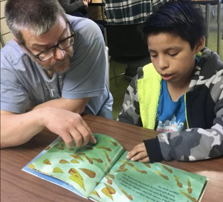 A mentor and a student reading a picture book together during an after-school session